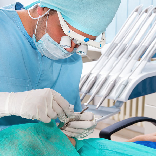 an oral surgeon operating on a dental patient